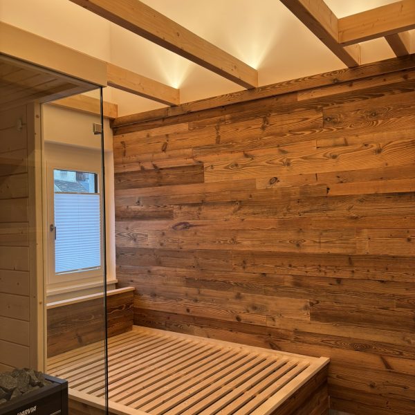 a wooden room with a glass door and a bed